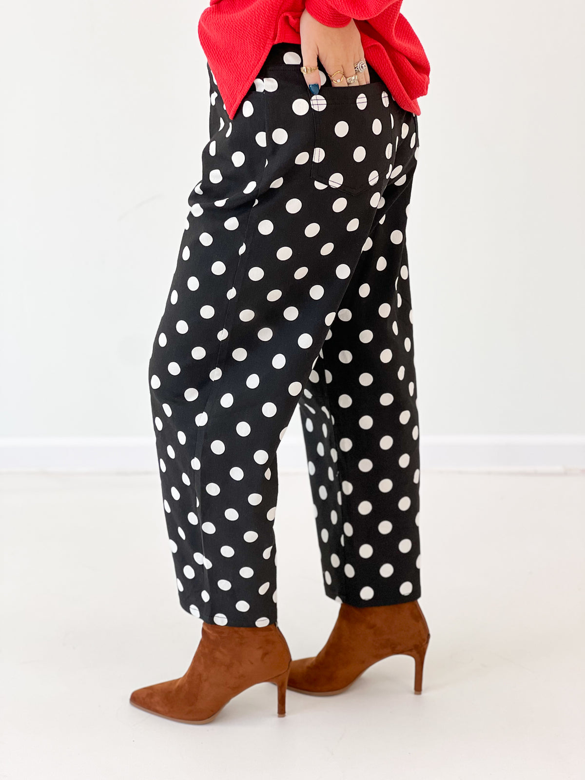 Black high-rise straight-leg polka dot pants with white dots, close-up hem