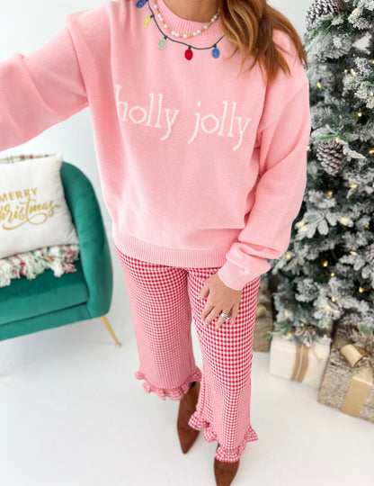 Pink crew neck sweater with “holly jolly” print, styled with red-and-white gingham pants