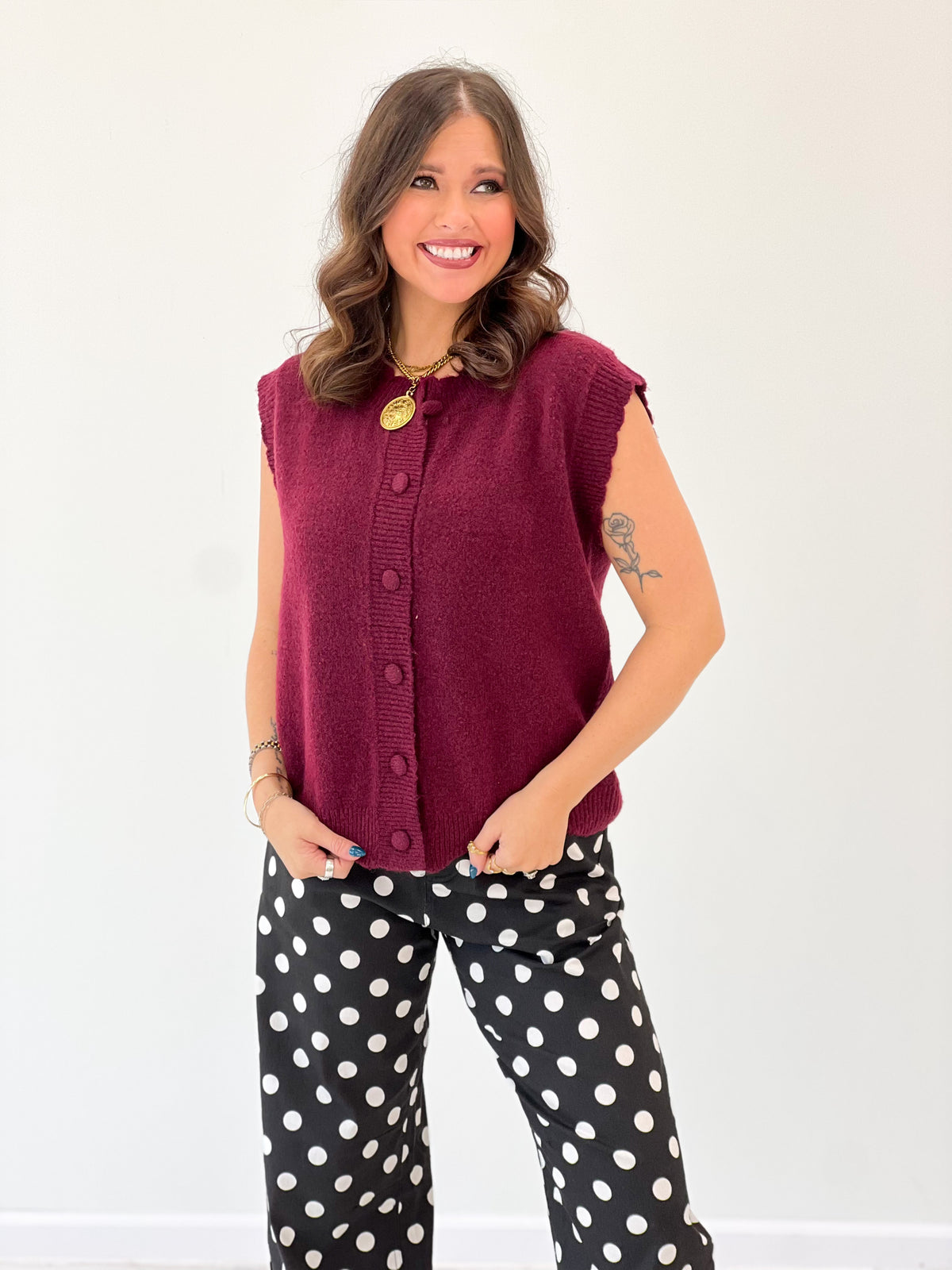Burgundy ribbed button-up sweater vest with scalloped armholes and round gold buttons