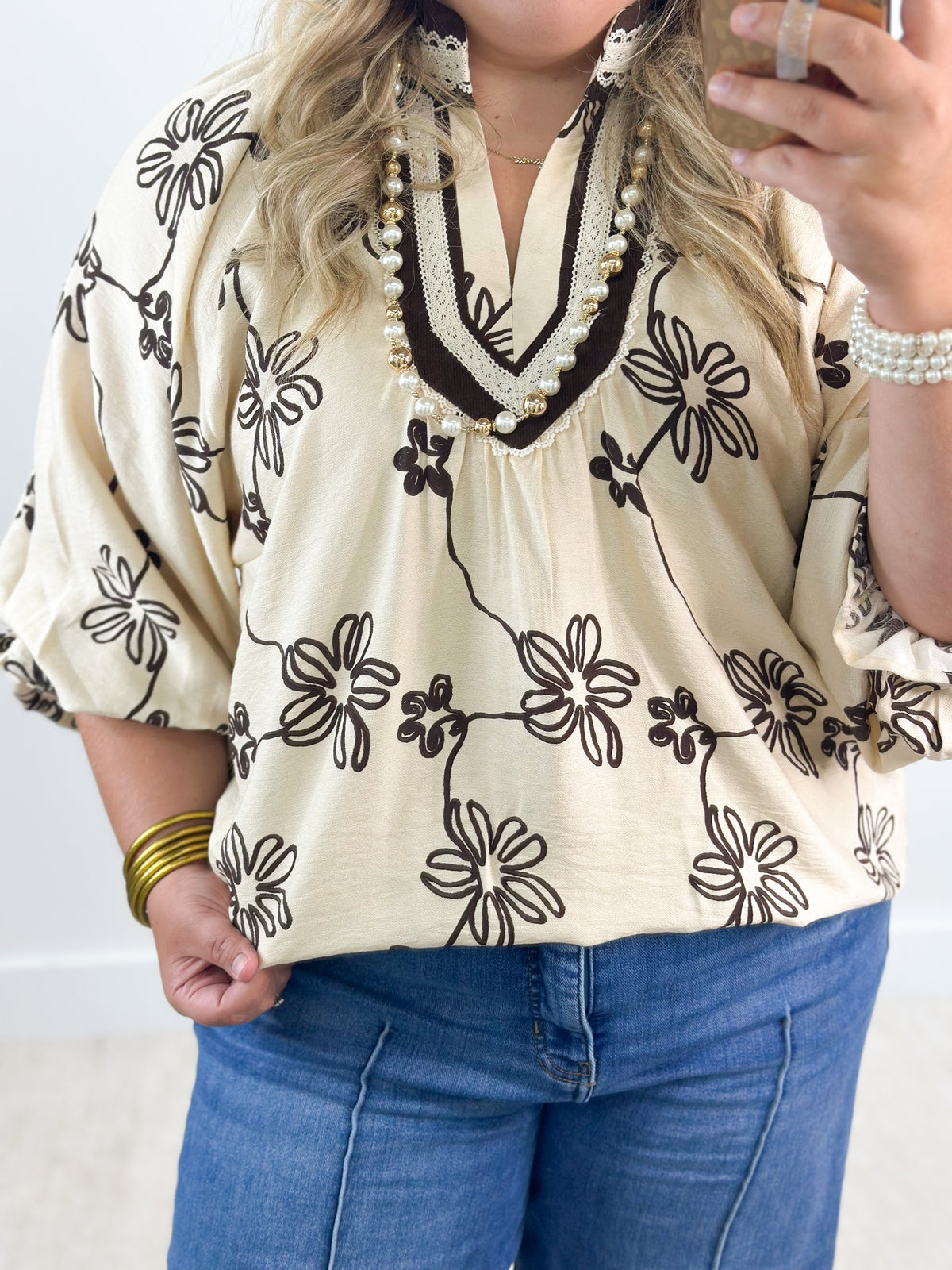Ecru floral print collared V-neck blouse with black daisy pattern and beaded trim