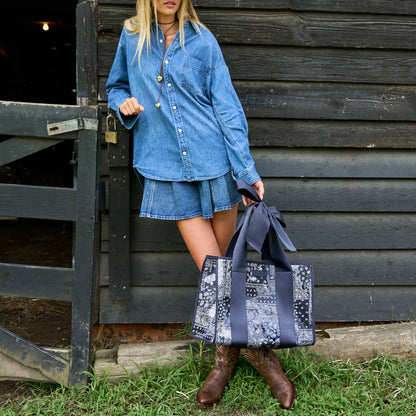 Patterned navy jelly tote bag with oversized bow closure and dual top handles.