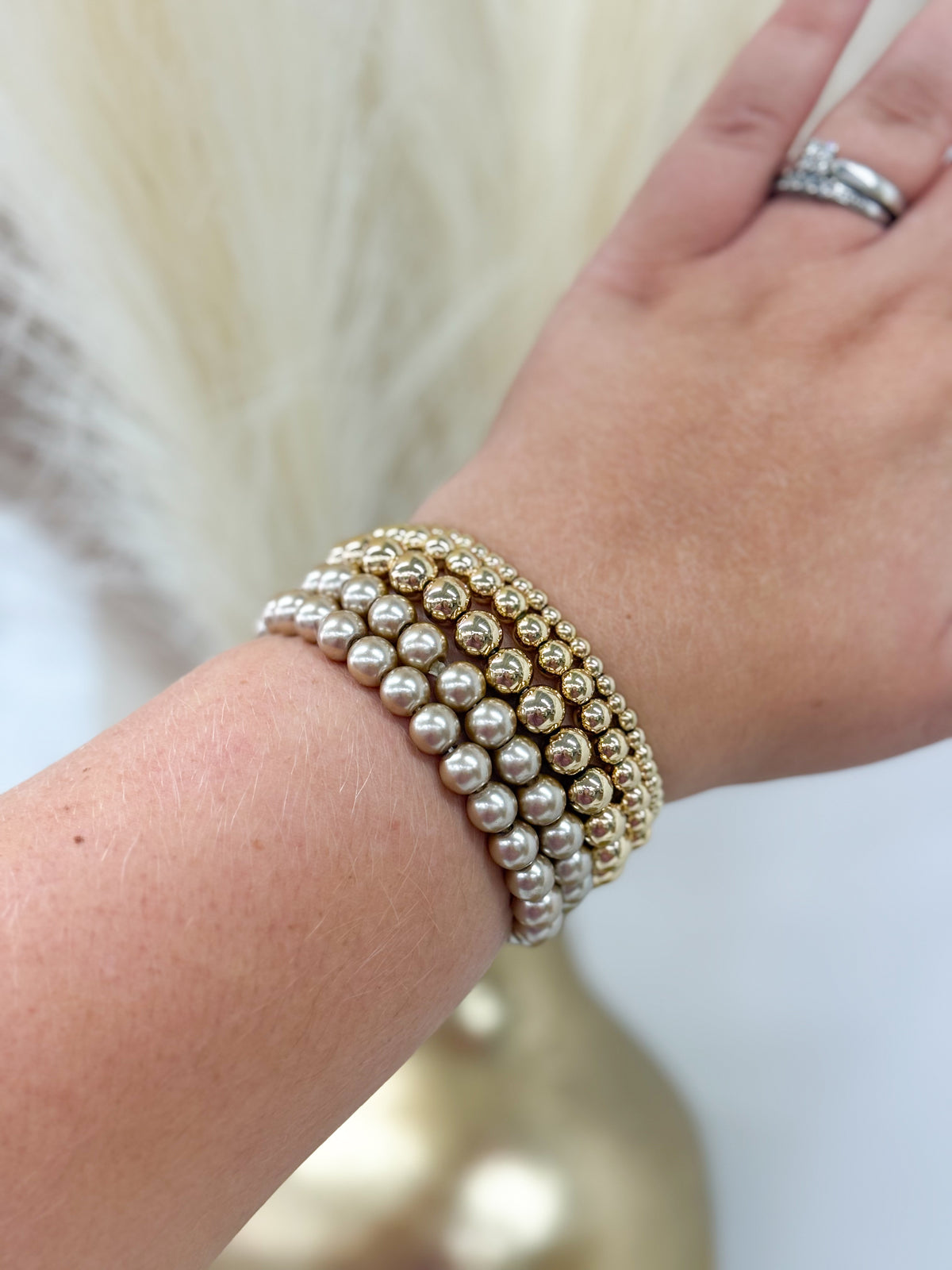Pearl and gold-toned 5-row bead bracelet worn on wrist