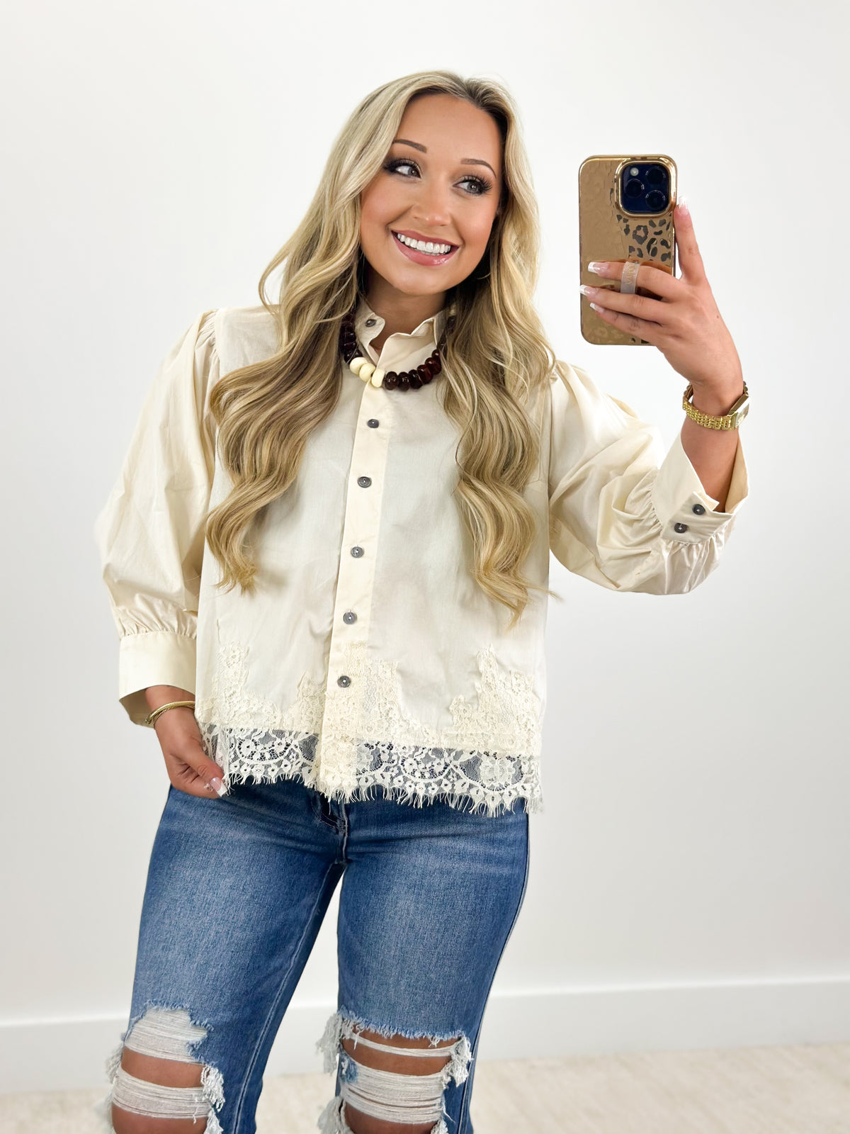 Ecru button-down top with lace hem, puff sleeves, and pearl-like button placket