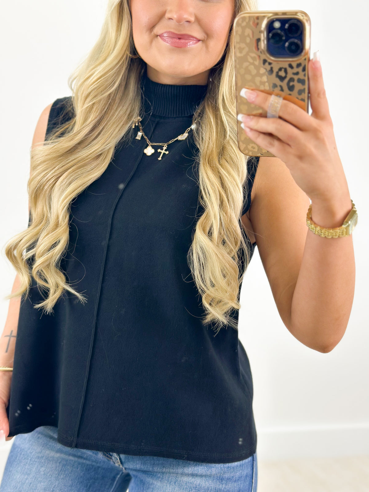Navy sleeveless turtleneck knit top with fitted bodice and high neckline
