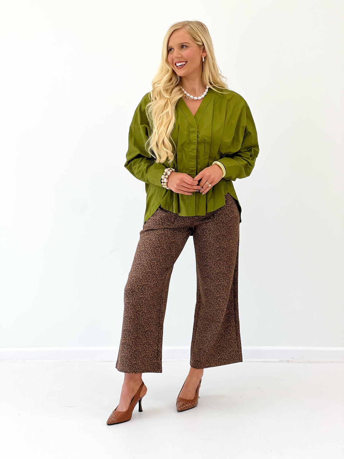 Olive green V-neck pleated-waist blouse with long sleeves and gathered yoke.