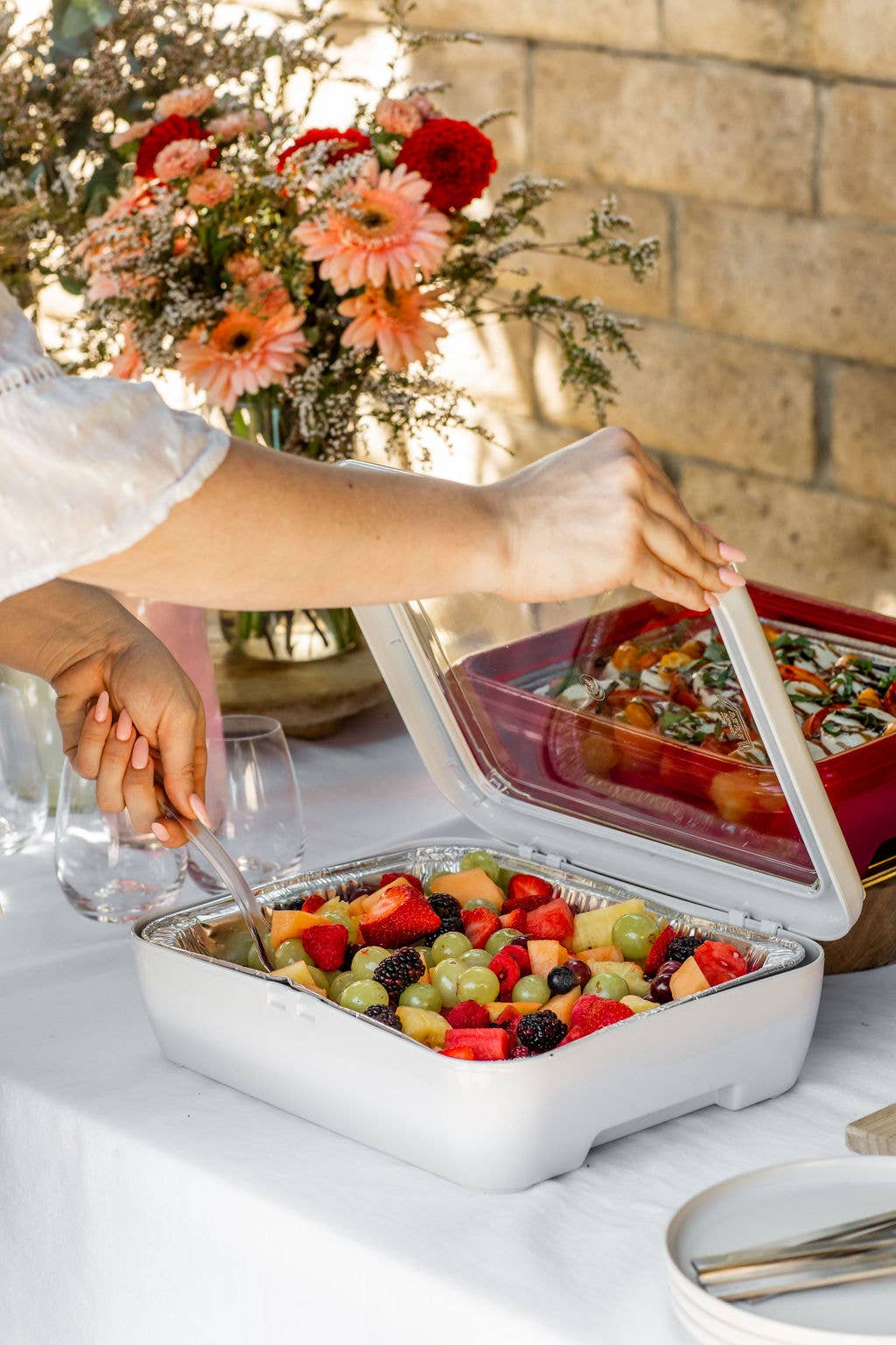 Insulated white food carrier holding foil pan with colorful prepared meal