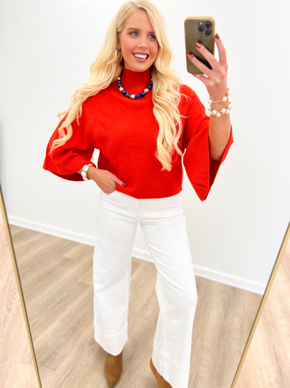 Red mock neck sweater with wide sleeves, featuring a clean crew neckline