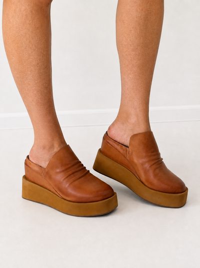 Tan leather platform mule shoes on feet with ruched upper