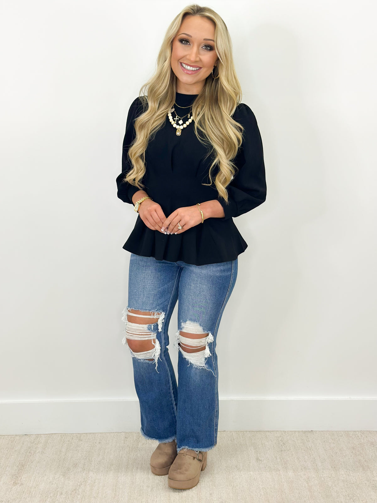 Black long-sleeve pleated flare top with ribbed trim at neckline and cuffs