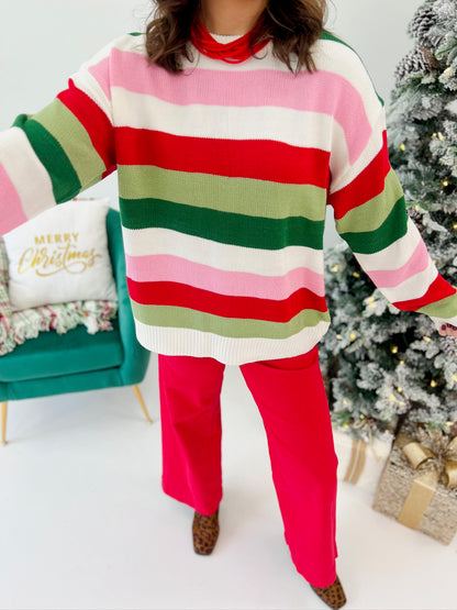 Multi-stripe knit Christmas sweater with pink, red, white, and green wide horizontal stripes
