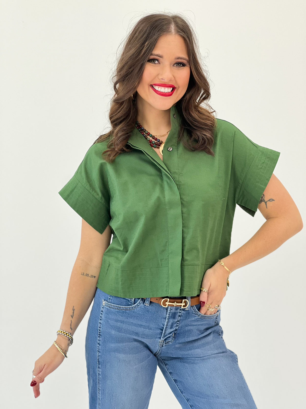 Green solid high-collar short-sleeve button-up top, close-up of collar and buttons