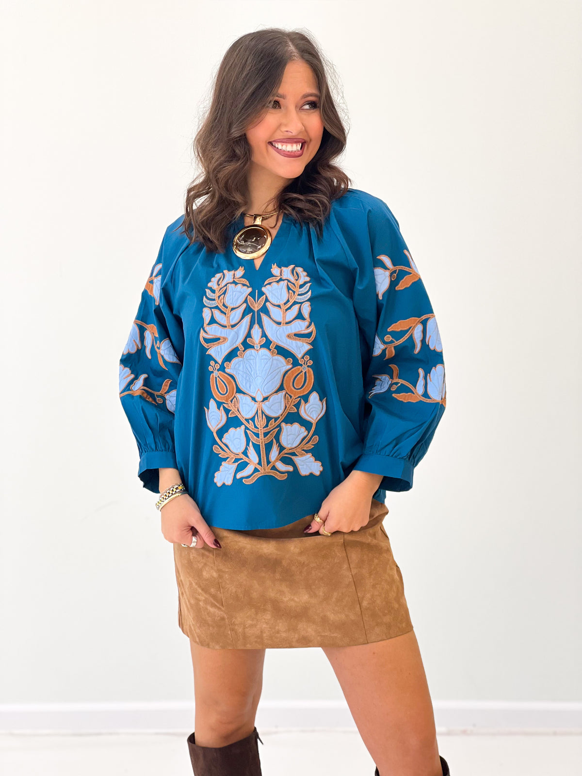 Teal notched V-neck top with baroque floral applique and long sleeves