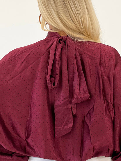Burgundy polka dot high-neck blouse with tie-back bow and long puff sleeves