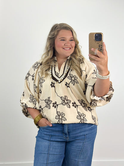 Ecru floral collared V-neck top with black flower print and tassel-tie neckline