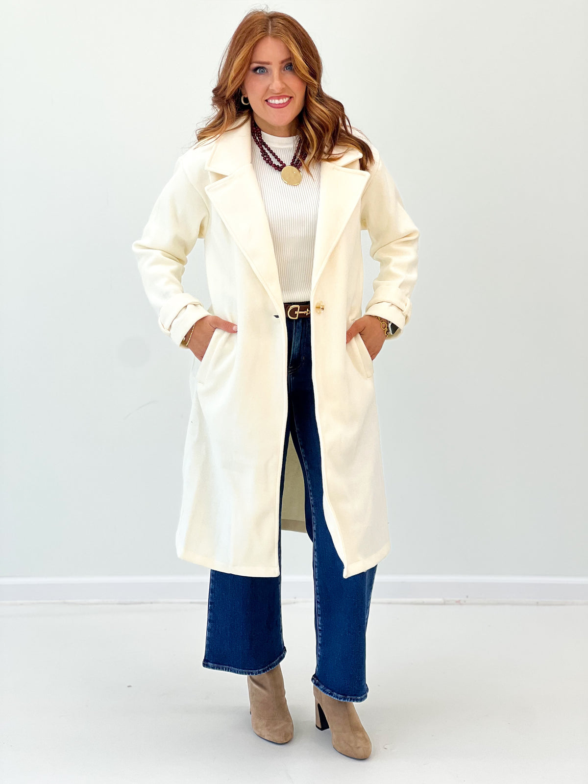 Cream longline coat with notch collar, button front, and side pockets
