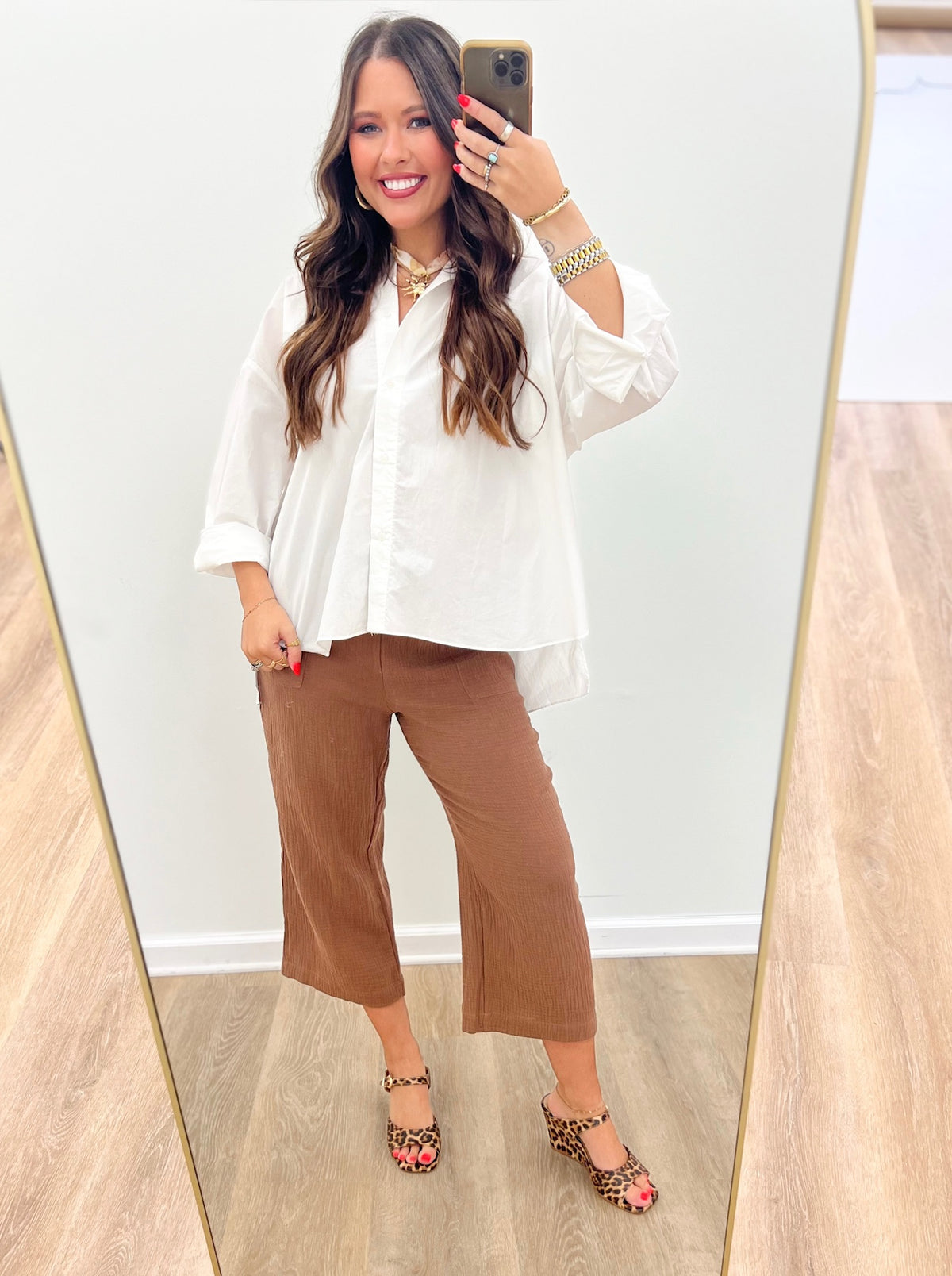 White collared button-down top with button front, worn with brown pants