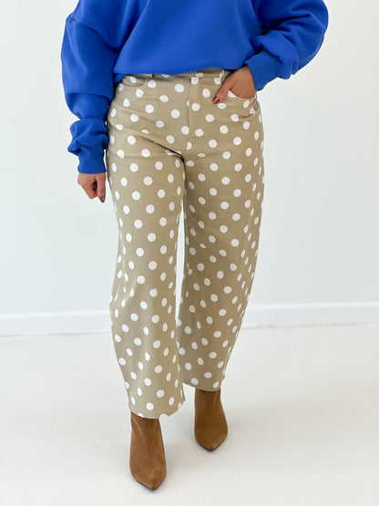 Taupe high-rise straight-leg polka dot pants with white dots, close-up legs