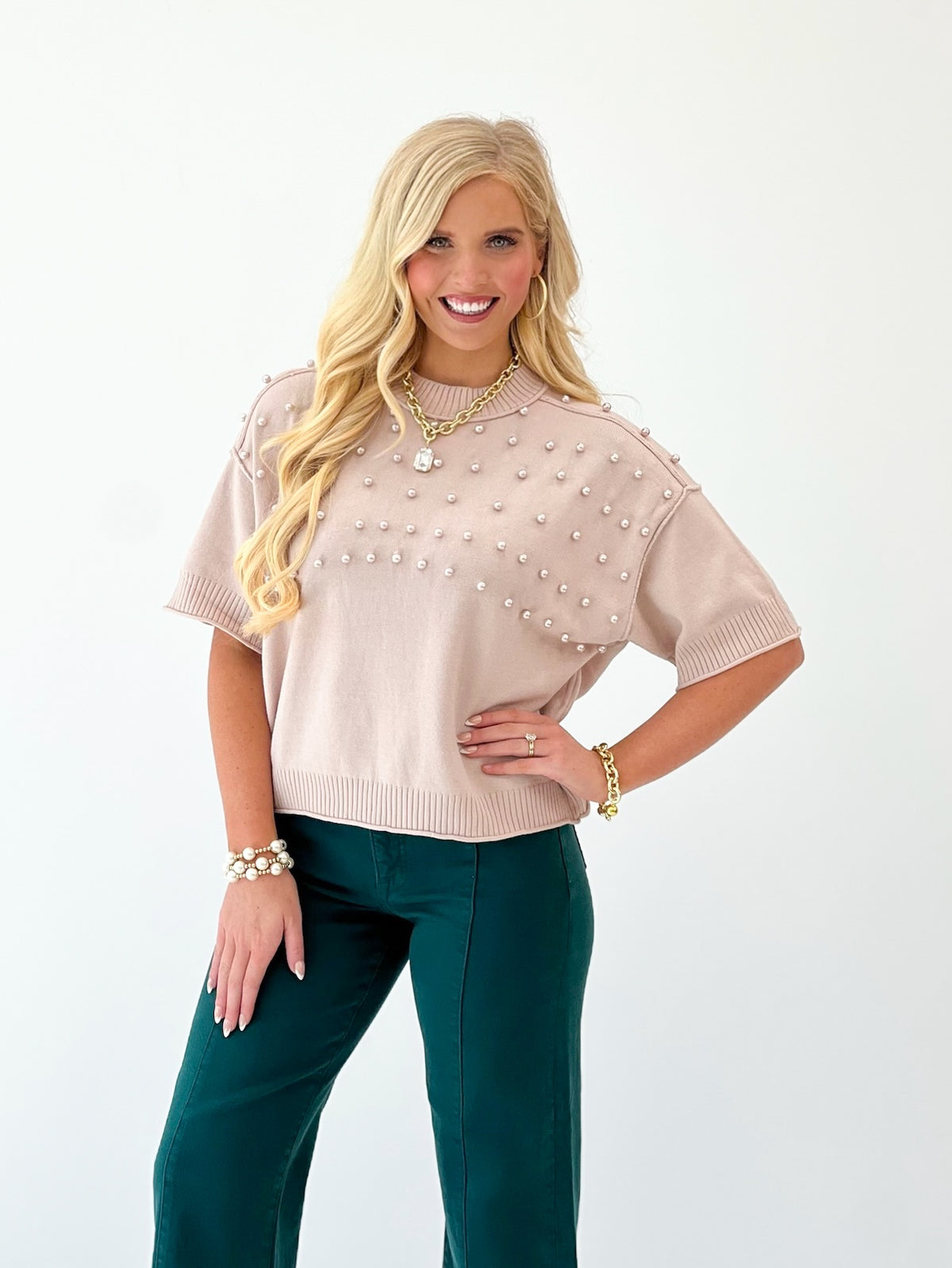 Beige knit crewneck sweater covered in pearl studs, ribbed collar and cuffs