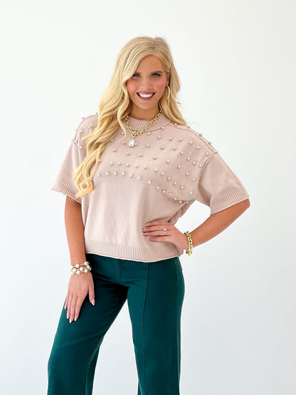 Beige knit crewneck sweater covered in pearl studs, ribbed collar and cuffs