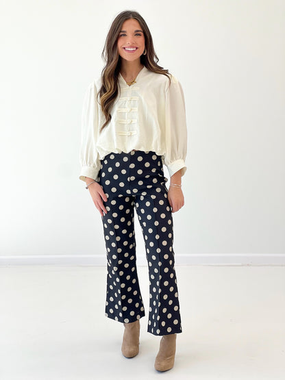 Cream blouse with tiered ruffle placket, gathered neck, and voluminous sleeves with cuffs