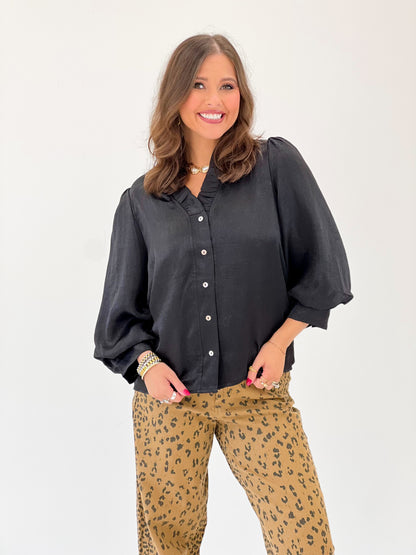 Black V-neck button-front top with puff sleeves and visible round buttons