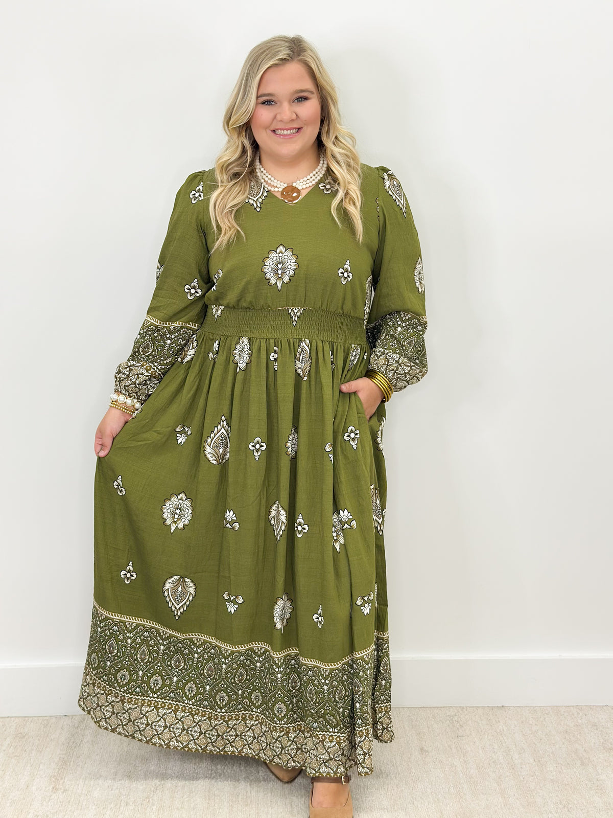 Olive green border print midi dress with long sleeves, gathered waist, patterned hem border