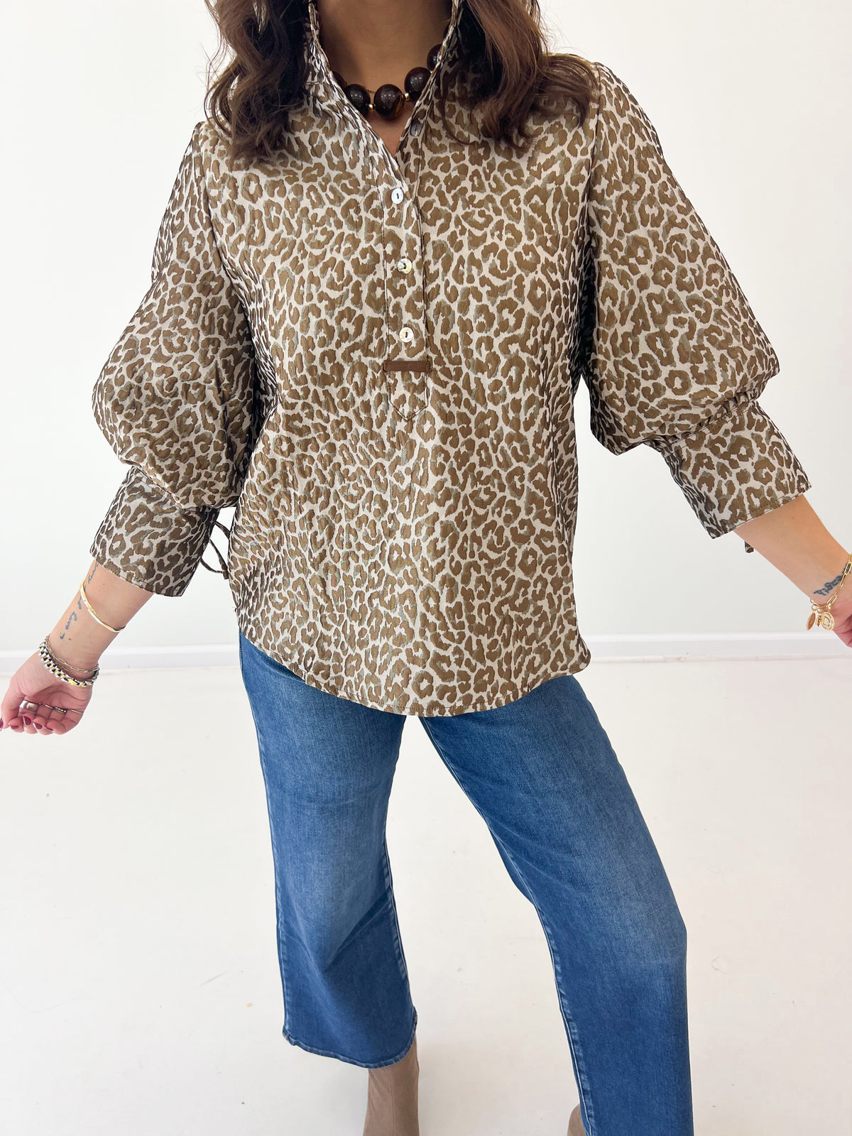 Taupe leopard jacquard button-up top with half-button placket and puff sleeves.