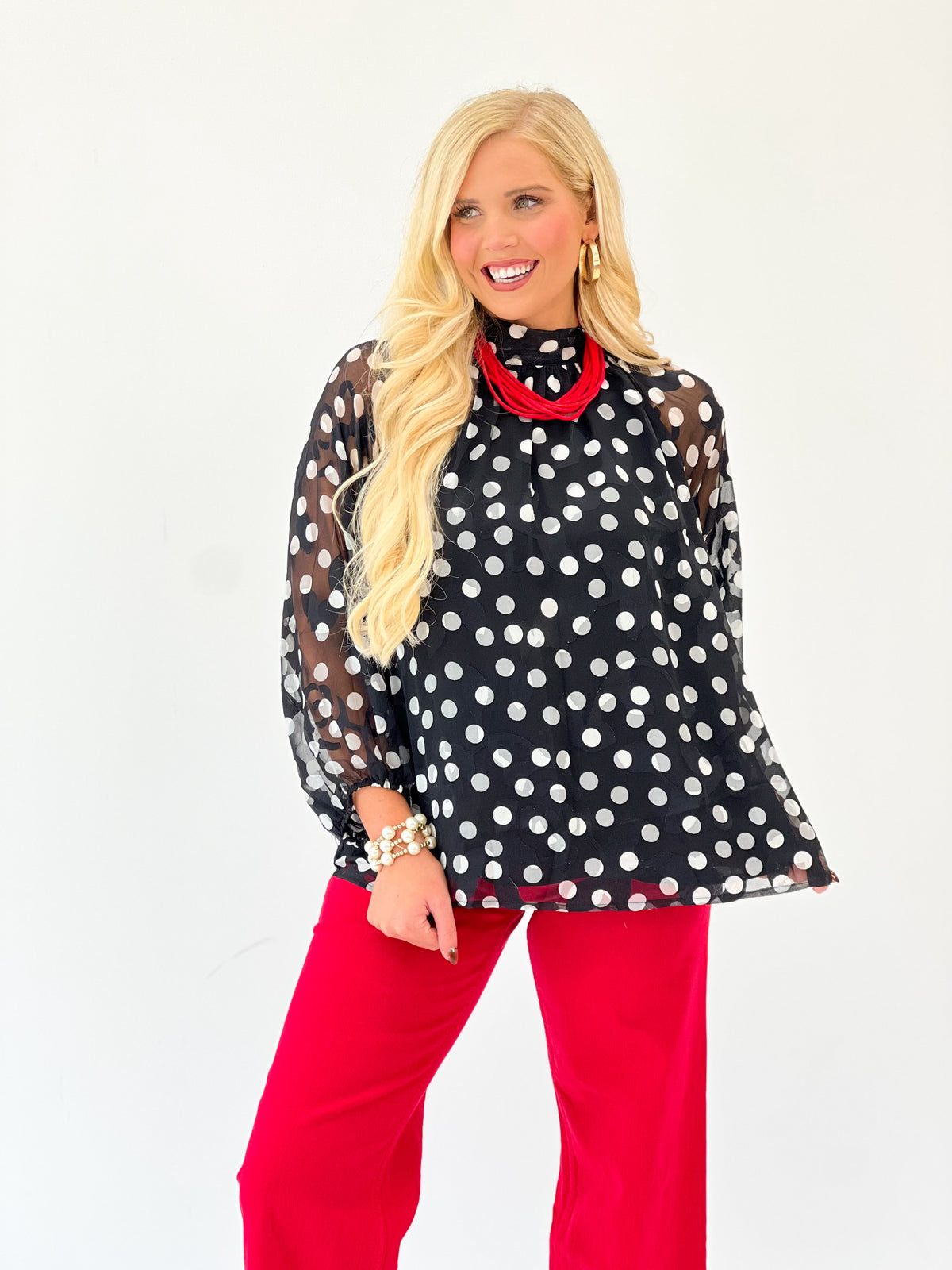 Black polka dot high-neck long-sleeve blouse with red contrast collar and cuffs