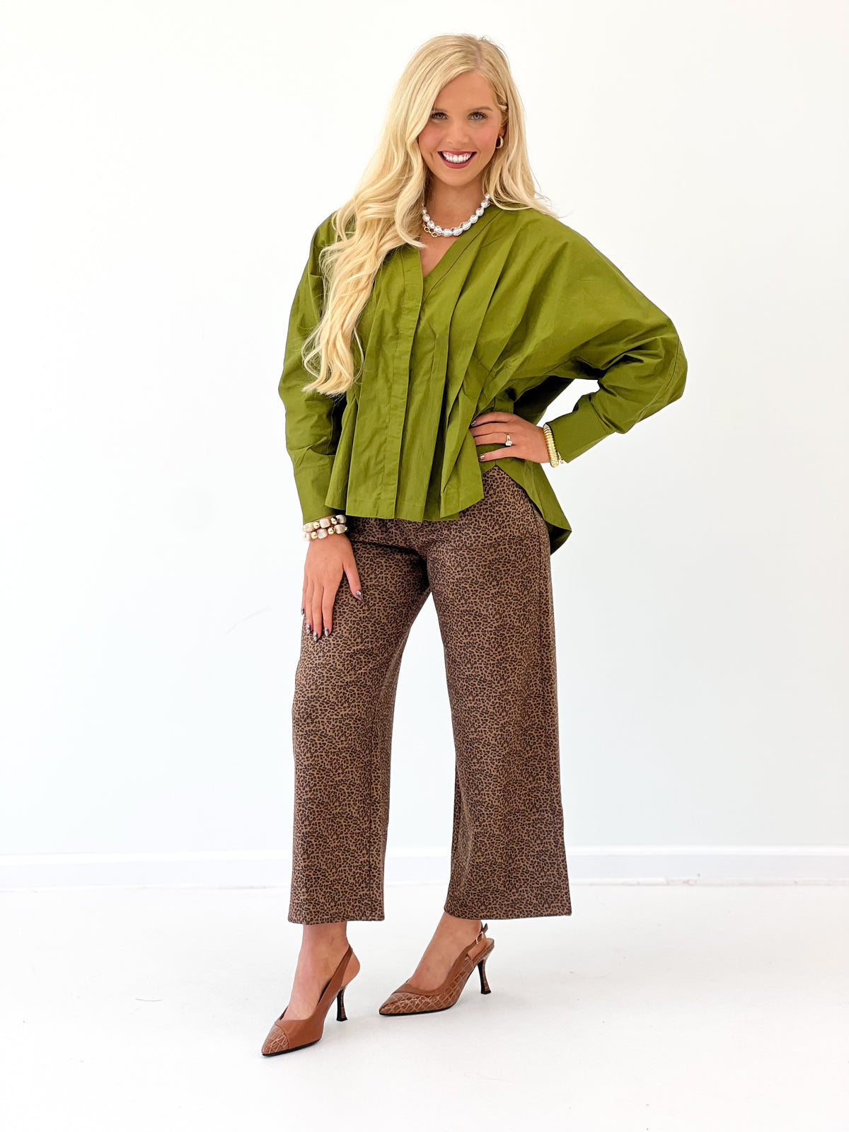 Olive green V-neck pleated-waist blouse with long sleeves and buttoned front.