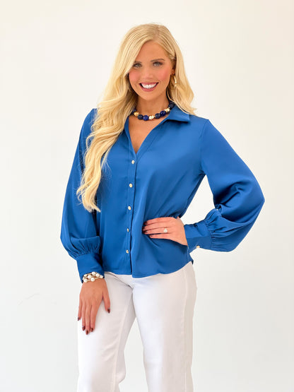 Blue satin button-up V-neck top with long sleeves and front button placket