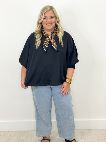 Black v-neck oversized top with cuffed sleeves, loose fit over light jeans