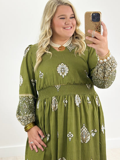 Olive green long-sleeve border print dress with patterned hem border and motif skirt