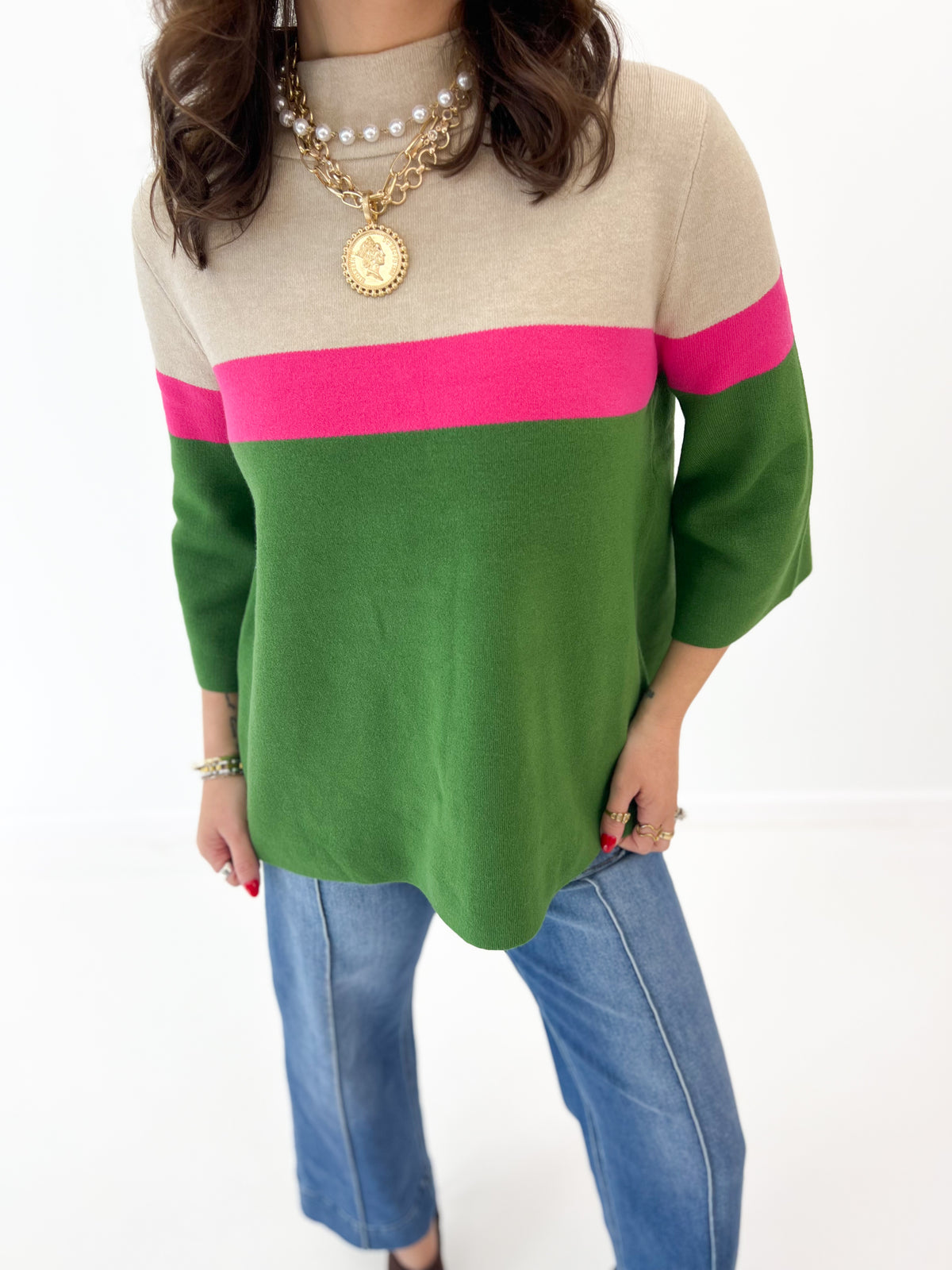Color-block mock neck sweater with beige top, green body, and pink stripe band
