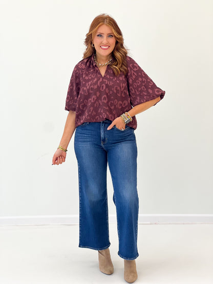 Maroon textured jacquard split-neck top with puff sleeves and allover animal print