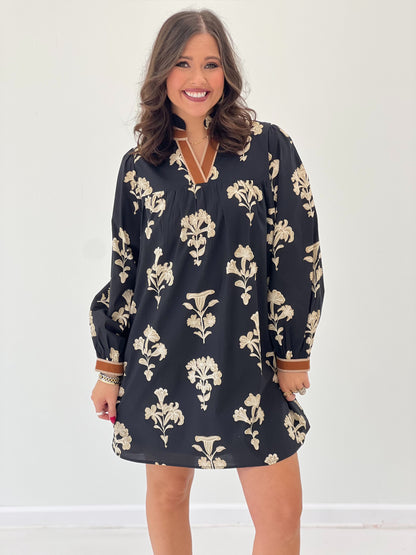 Black floral V-neck ruffle-collar dress with decorative neckline trim and cuffed sleeves.