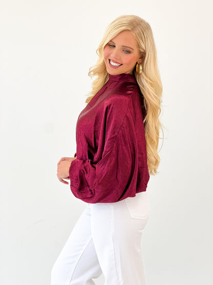 Burgundy polka dot high-neck blouse with tie-back detail and puff sleeves