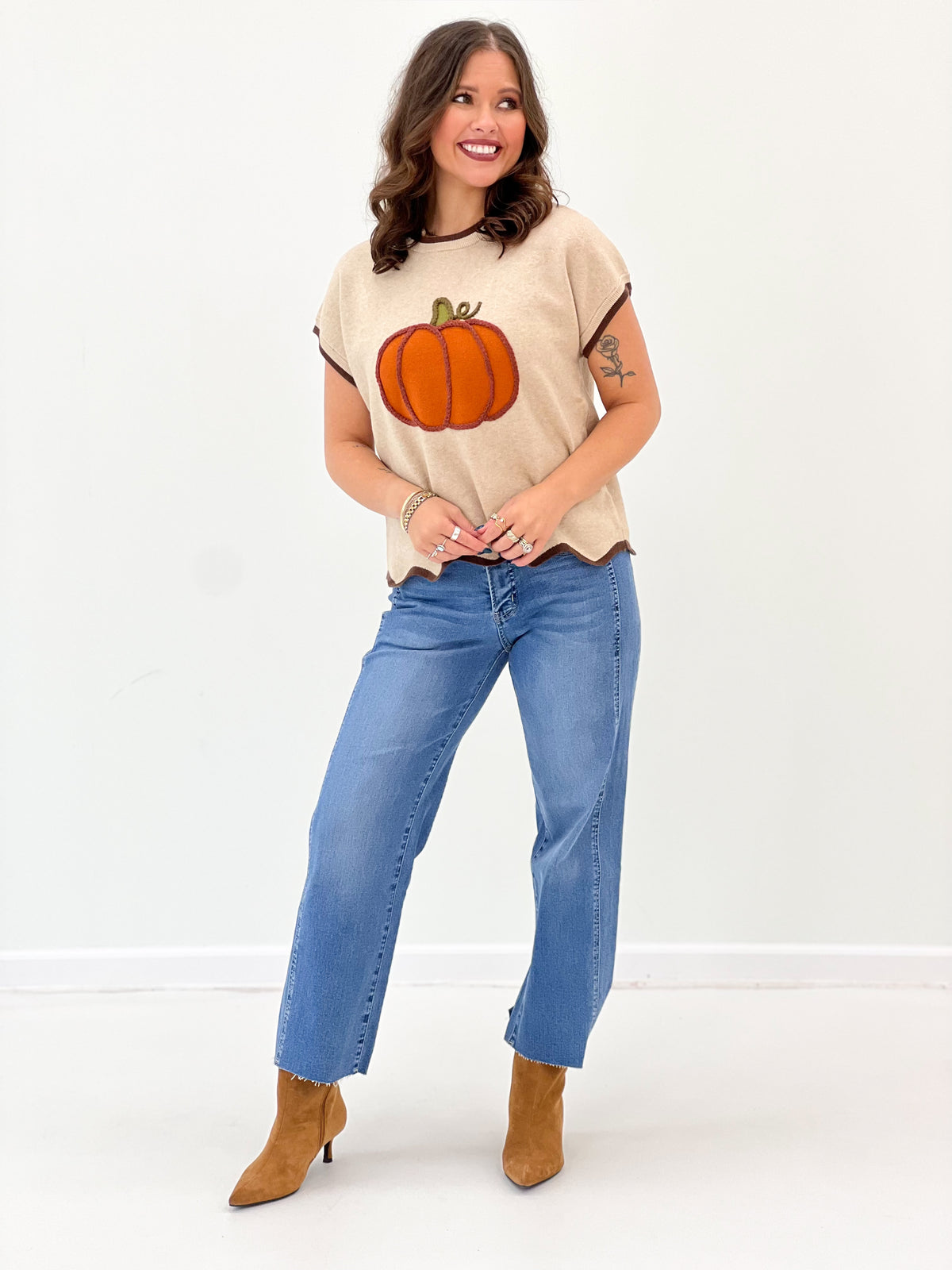 Light taupe pumpkin sweater top with short sleeves and scallop hem; worn with jeans