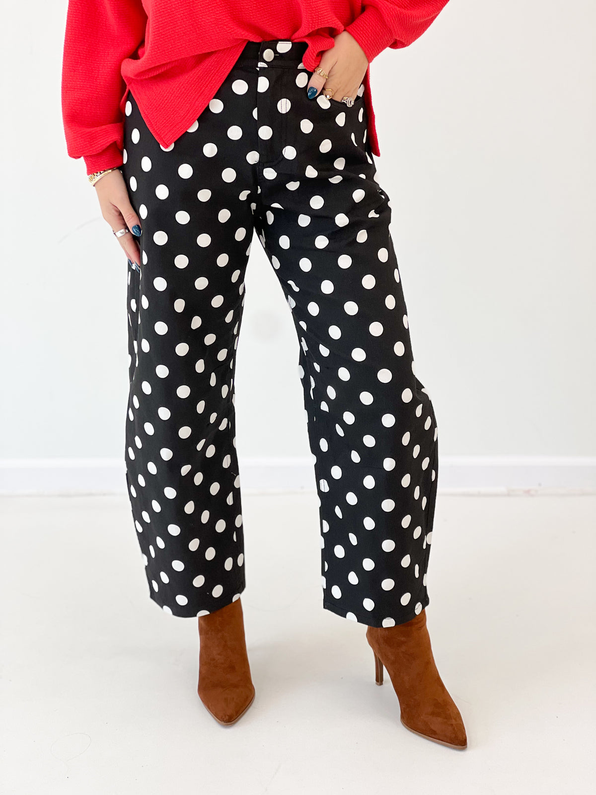 Black high-rise straight-leg polka dot pants with white dots, close-up lower half