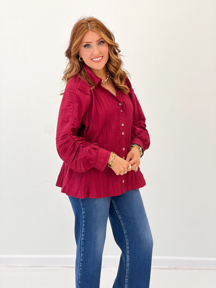 Burgundy ruched button-up V-neck top with long puff sleeves and flared hem