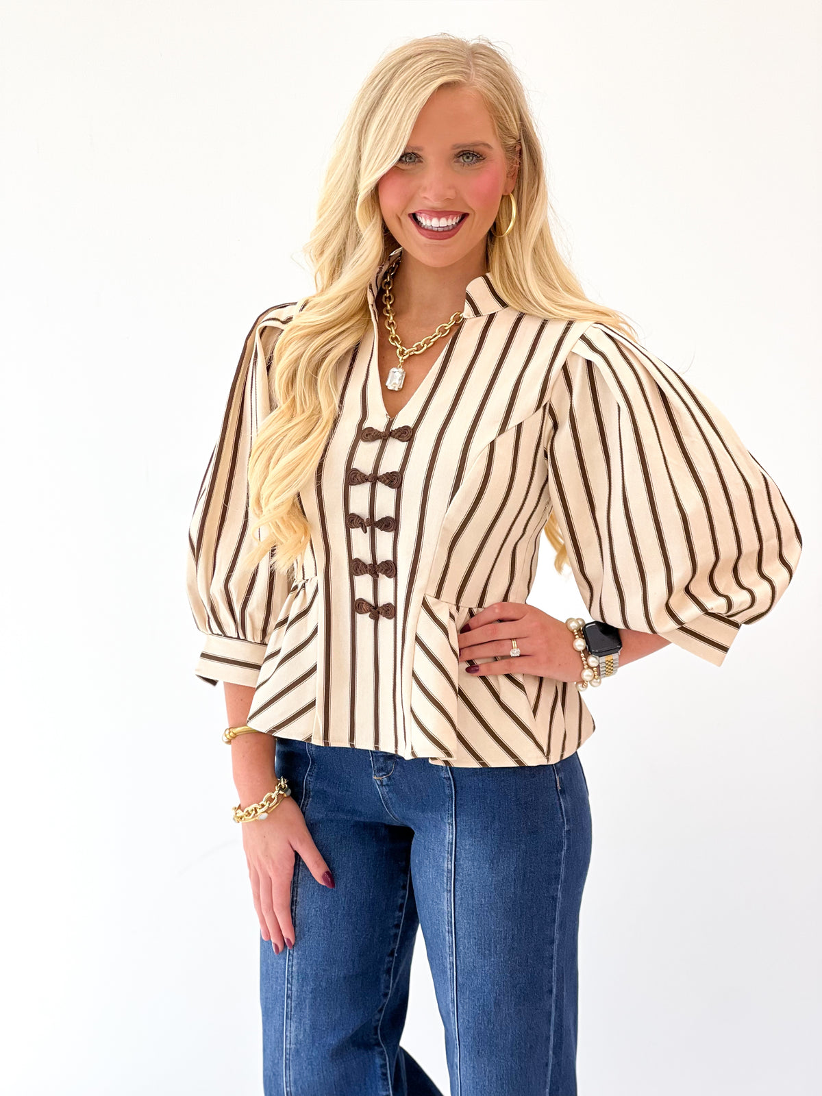 Brown-and-cream striped blouse close-up with puff sleeves and decorative front eyelets