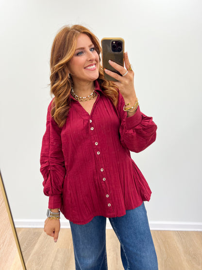Burgundy ruched button-up V-neck top with long puff sleeves and front buttons