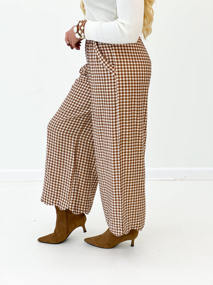 Red and white checkered wide-leg pants shown from the side, loose pleated leg opening