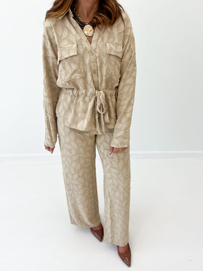 Taupe elastic tie-waist wide-leg pants with leaf pattern, three-quarter view.