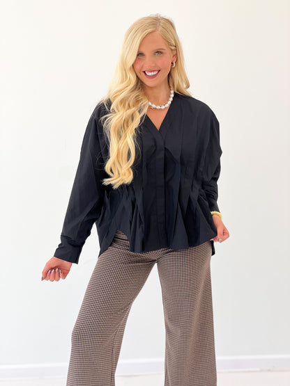 Black V-neck pleated-waist blouse with long sleeves and ruffled chest detail.