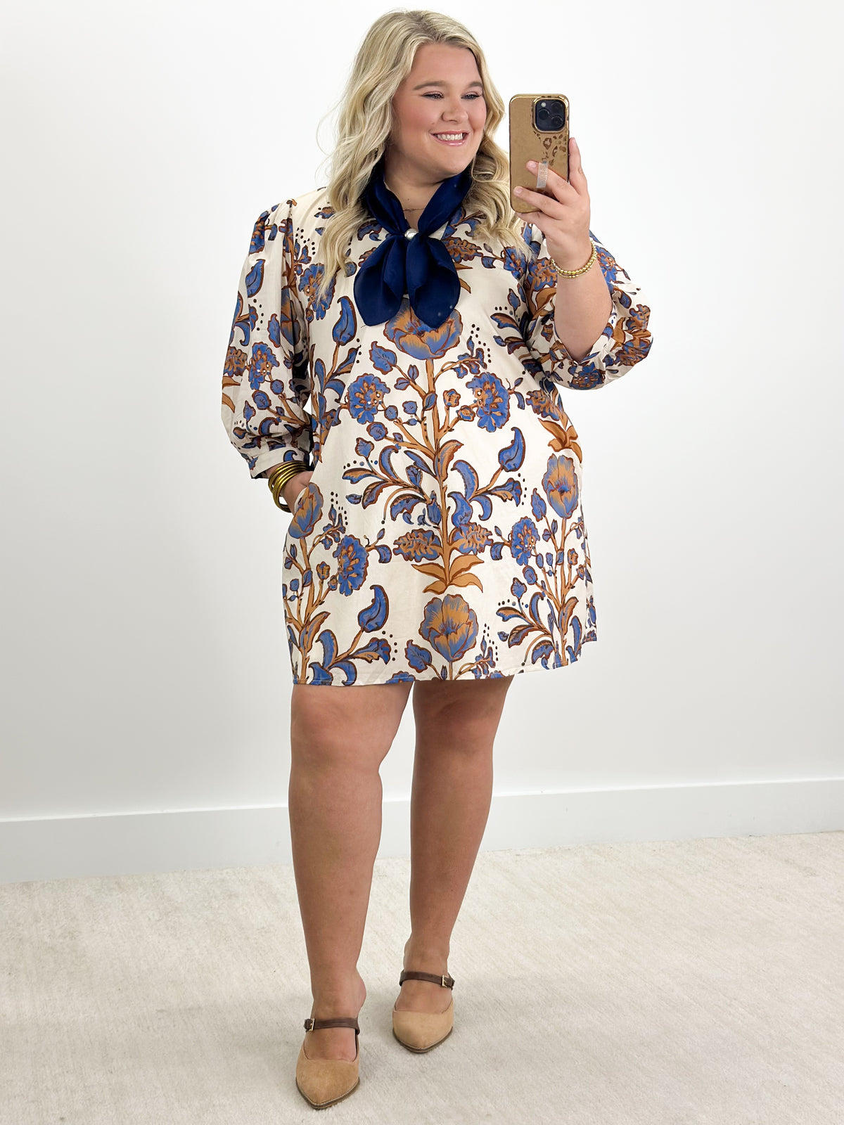 Ecru floral mini dress with navy tie-neck bow and puff sleeves, full-body