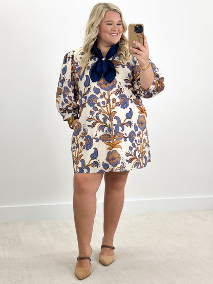 Ecru floral mini dress with navy tie-neck bow and puff sleeves, full-body