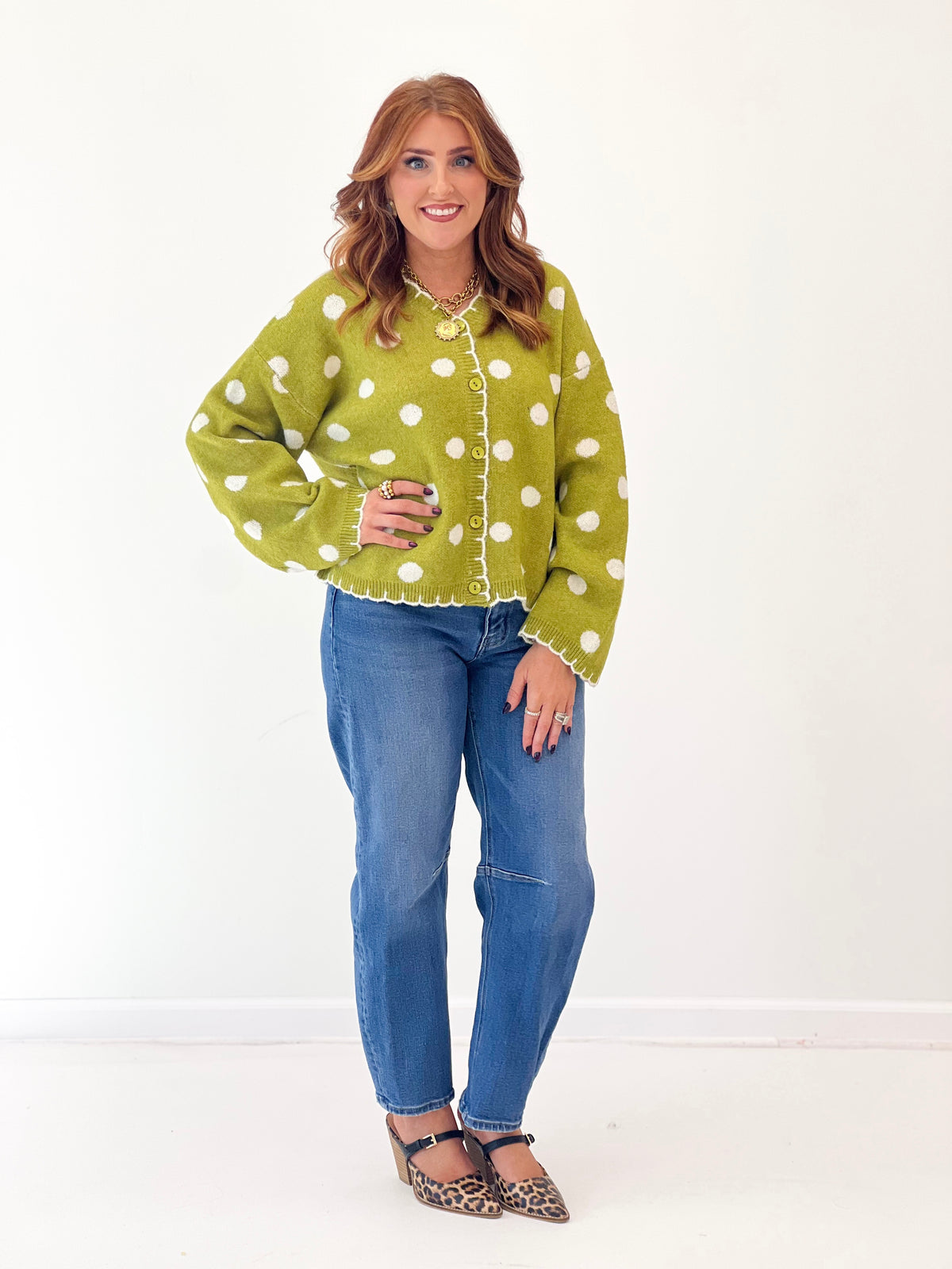 Green polka dot button-front cardigan with long sleeves and scalloped cuffs.