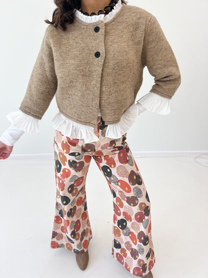 Mocha knitted cardigan close-up: black button front, white ruffle cuff and hem