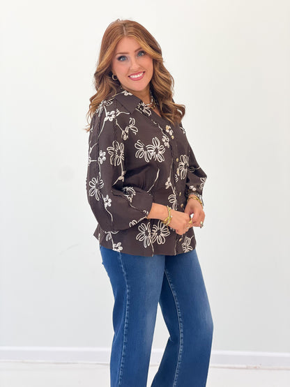 Dark brown floral button-front blouse with long sleeves and curved hem