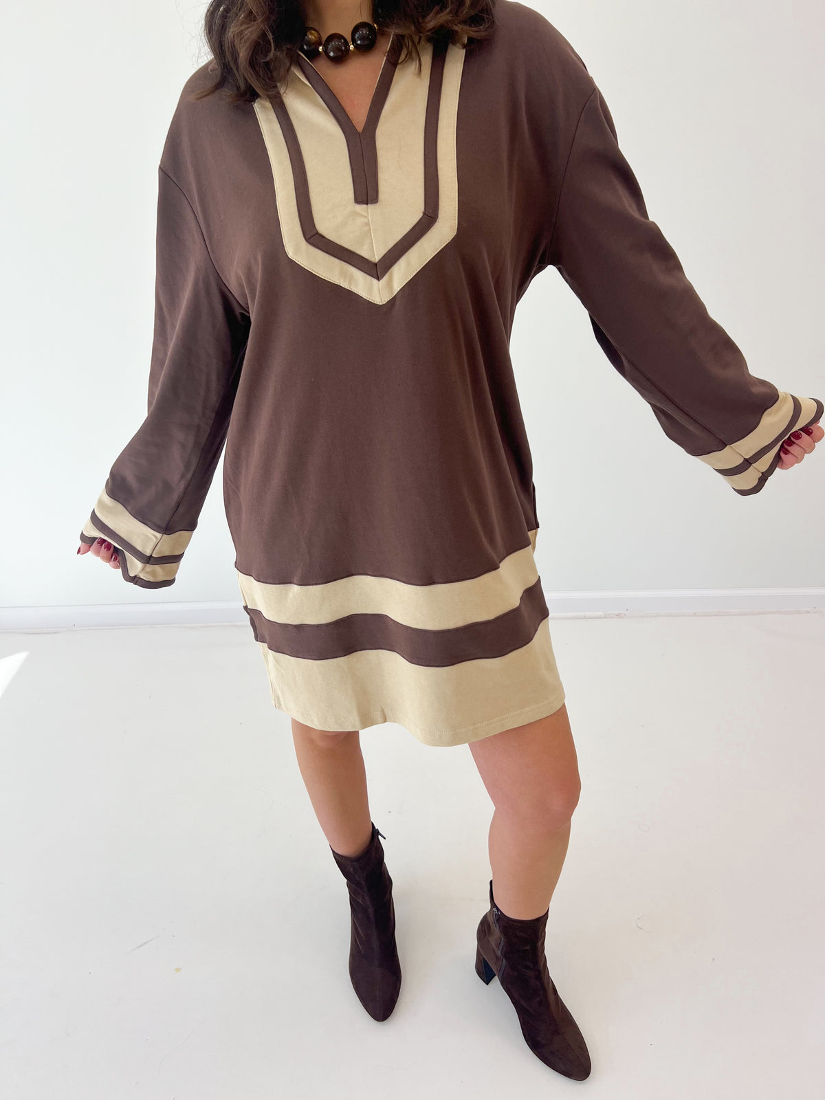 Brown V-neck sweatshirt dress with cream color-block trim at collar, cuffs, and hem